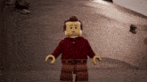 a lego man in a red sweater and brown pants