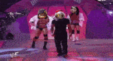 a man and two women are walking down a stage with a sign that says wwe on it