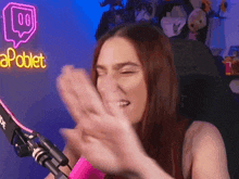 a woman is clapping in front of a neon sign that says apoblet