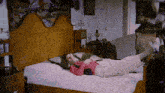 a woman in a pink shirt is laying on a bed with her feet up