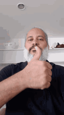 a man with a beard and mustache holds his hand to his nose