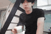 a man in a black shirt is holding a cup in his right hand