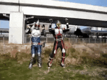 two kamen riders are jumping in the air in front of a bridge .