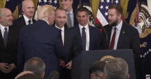 a man in a suit and tie shakes hands with a man in front of a podium that says united states of america
