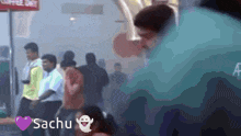 a group of people standing in a line with the name sachu on the bottom left