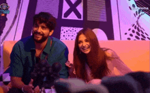 a man and a woman are sitting next to each other on a couch and smiling at the camera .