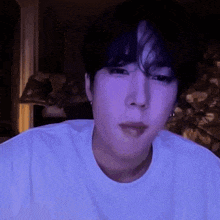 a close up of a person 's face with a purple light behind him .