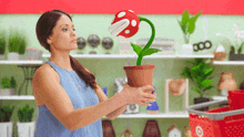 a woman is holding a potted plant with a piranha plant in it