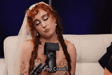 a woman with red hair is sitting in front of a microphone and says pop crave