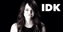 a woman is making a funny face in front of a black background with the word idk .