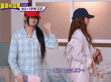 a girl wearing a red hat stands next to another girl wearing a blue hat
