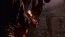 a man in a brown shirt is holding another man 's hand in a dark room .