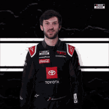 a man in a toyota racing suit is smiling for the camera