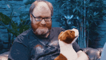 a man with glasses holds a stuffed dog