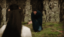 a man in a black robe is kneeling down in front of a woman