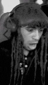 a man with dreadlocks is wearing headphones and a hat .