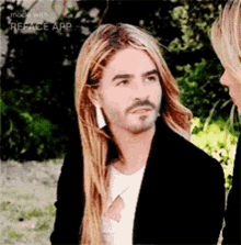 a man with long blonde hair and a beard is looking at a woman .