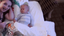 a woman is laying in a hospital bed with a baby in a crib .