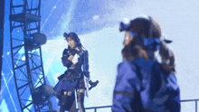 two women are standing on a stage holding microphones .