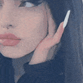 a close up of a woman 's face with a nose ring and a white nail polish .