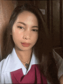 a woman wearing a white shirt and a red bow tie looks at the camera
