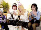 three women are sitting on a couch with one wearing a hat that says ' snoop dogg ' on it