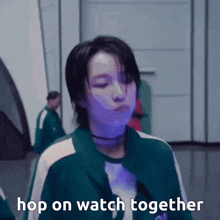 a woman in a green jacket is standing in front of a wall and says hop on watch together