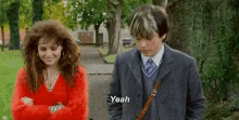 a man and a woman are standing next to each other and the man is saying yeah