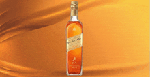 a bottle of johnnie walker gold label whiskey on an orange background