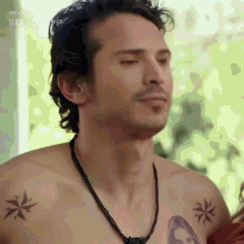 a man without a shirt has a tattoo of a woman on his shoulder