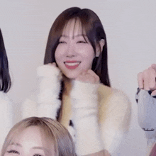 a woman in a white sweater is smiling while sitting next to a group of girls .