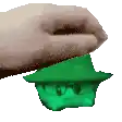a hand is holding a green frog wearing a hat and glasses .