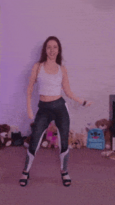 a woman is dancing in front of stuffed animals including a blue backpack that says stitch