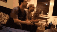 two men are playing a video game on a couch .