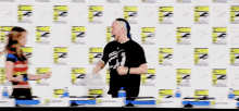 a group of people are standing in front of a wall with comic con logos on it
