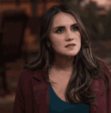 a woman wearing a burgundy jacket and a blue shirt