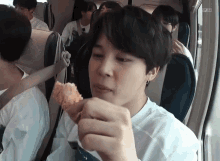 a young man is sitting on a plane eating a piece of chicken .