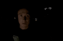 a man wearing headphones looks at a phone screen in the dark