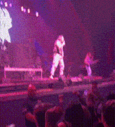 a man is standing on a stage in front of a crowd while a band plays behind him