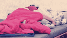 a person laying on a bed with a pink blanket