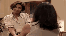 two women are standing next to each other in a living room and talking to each other .