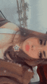 a woman is taking a selfie in a car with a star on her nose .