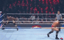 two men are wrestling in a wrestling ring with a referee watching .
