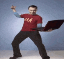 a man wearing a red shirt that says geek holds a laptop