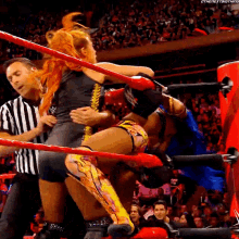 a woman is wrestling a man in a wrestling ring while a referee watches .