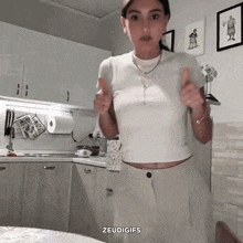 a woman giving a thumbs up in a kitchen with the words " zeudigifs " on the bottom