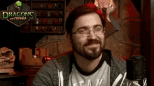 a man with glasses is smiling in front of a dragons and things sign