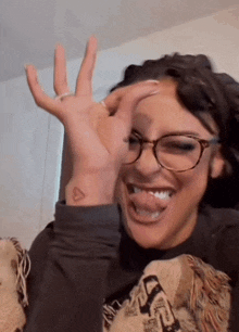 a woman with glasses and a small tattoo on her wrist is making a funny face