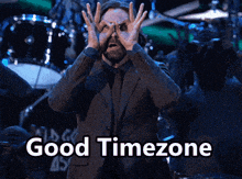a man in a suit and tie is making a funny face with the words good timezone behind him