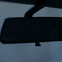 a person 's face is reflected in the rear view mirror